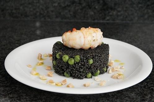 Schwarzes couscous mit erbsen und scampi