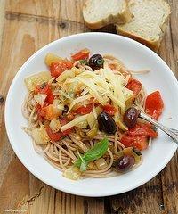 Dinkel-spaghetti mit zwiebeln, tomaten, frischem basilikum und kalamata-oliven