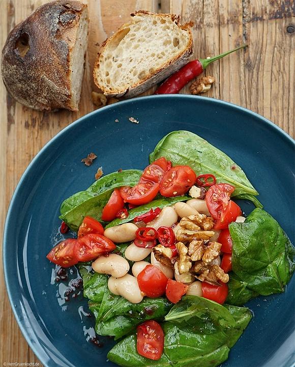 Spinatsalat mit weißen riesenbohnen, kirschtomaten, walnüssen und himbeermarmelade-peperoni-vinaigrette
