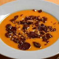 Süßkartoffel-suppe mit salami-chips, gerösteten erdnüssen und tomatenpesto