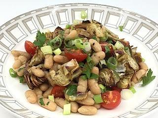 Italienischer bohnensalat mit tomaten und gebratenen artischocken