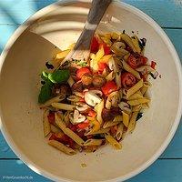 Mediterraner nudelsalat mit paprika rot und gelb, tomaten und gebratenen pilzen