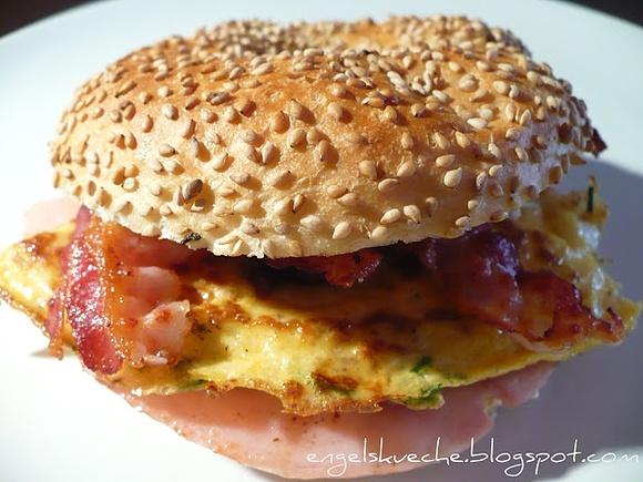 Frühstücks-bagel mit frischkäse, rührei, schinken und speck