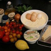 Ravioli gefüllt mit Kräuter-Zitronen-Ricotta auf buntem Tomatengemüse